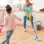 Mother and daughter dancing while mopping